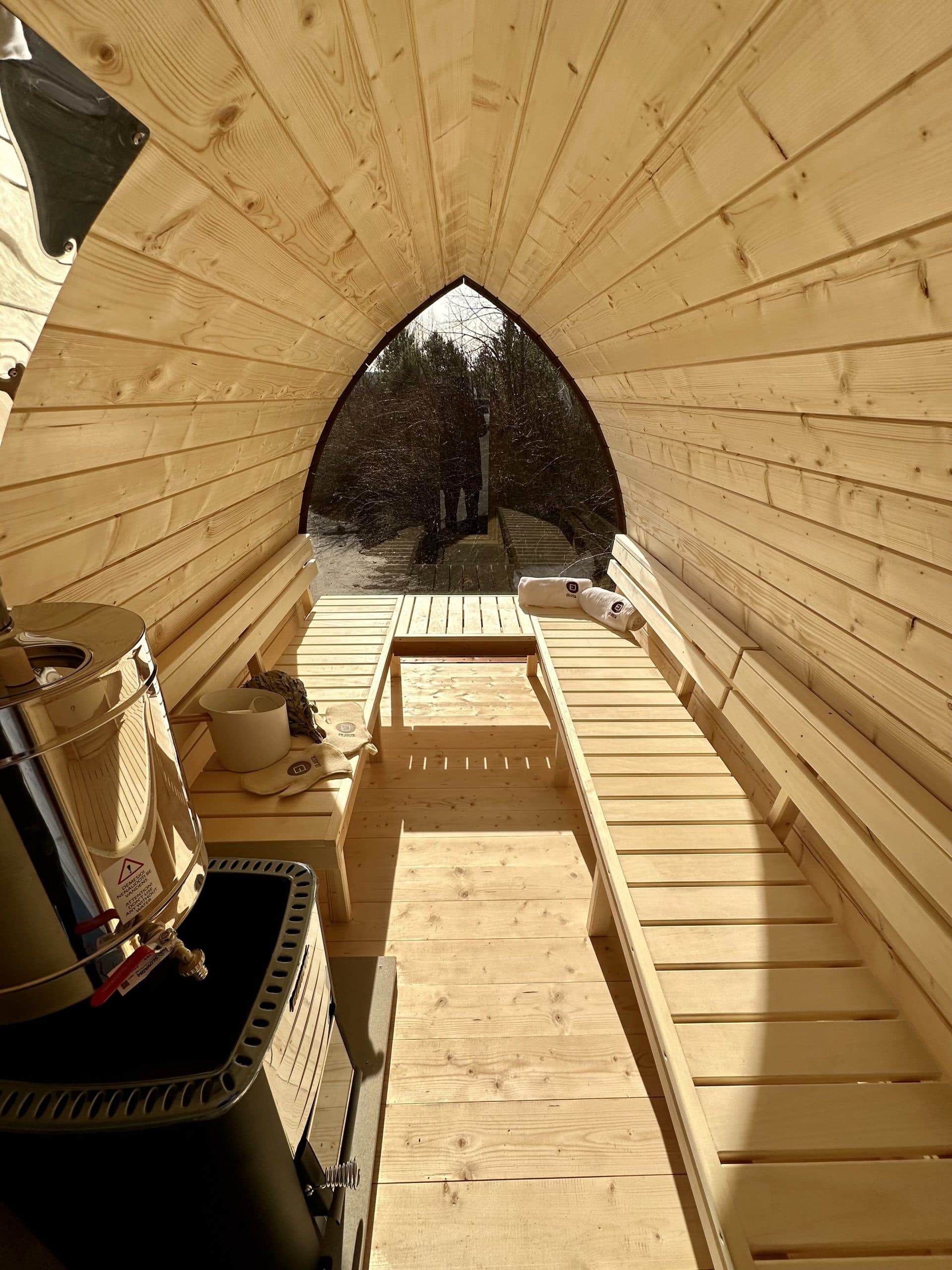 Interior of a pod mobile sauna with timber benches and a panoramic window